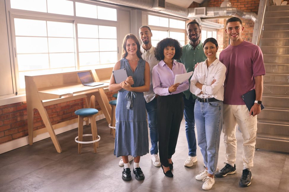 Portrait Of Smiling Multi-Cultural Business Team In Modern Open Plan Office Together